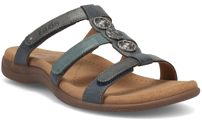 Leather slide sandal with three straps, each adjustable with velcro, embellished with three metal decorative accents.