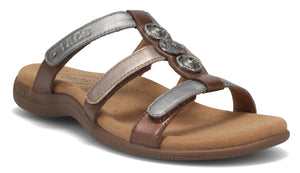 A brown sandal with three silver straps and decorative metal medallions.