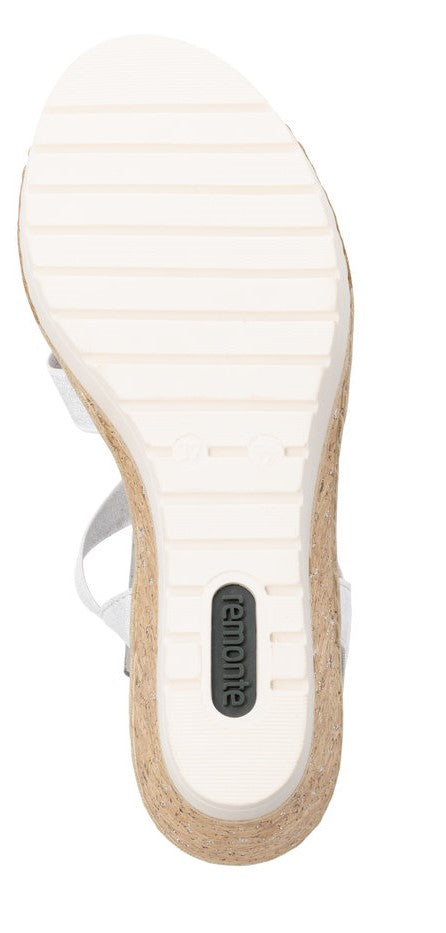 Bottom of a sandal with a white, ridged sole and light brown cork wedge.