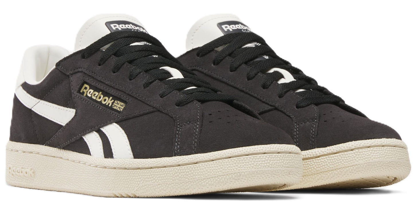 Pair of black sneakers with white side stripes, off-white soles and laces.