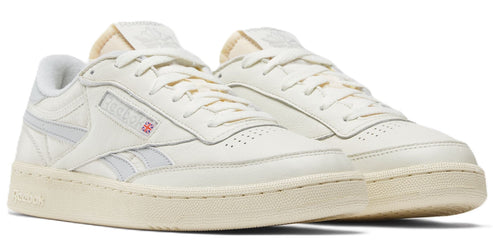 A pair of off-white sneakers featuring laces, a textured sole, and subtle side stripes.