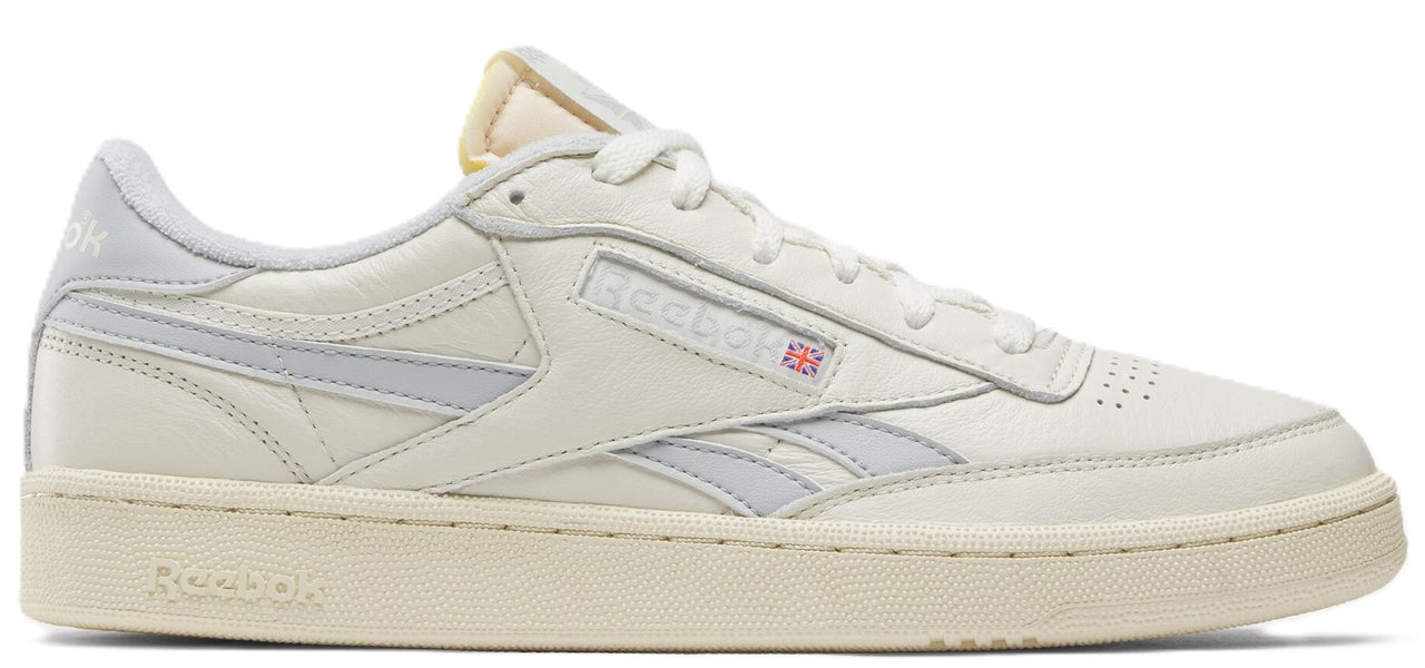 A sneaker in off-white with grey stripes.