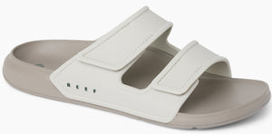 A sandal with two white velcro straps on a grey sole.