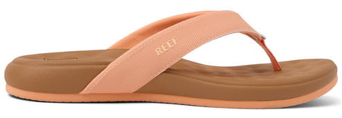 A peach-colored sandal with REEF printed on the strap and a brown sole.