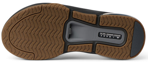 The bottom sole of a sandal showing a brown textured tread and gray bottle opener.