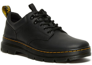 A black leather, low-top shoe with black laces, black eyelets, a pull tab on the heel with yellow text, and a thick, layered black sole with yellow stitching.