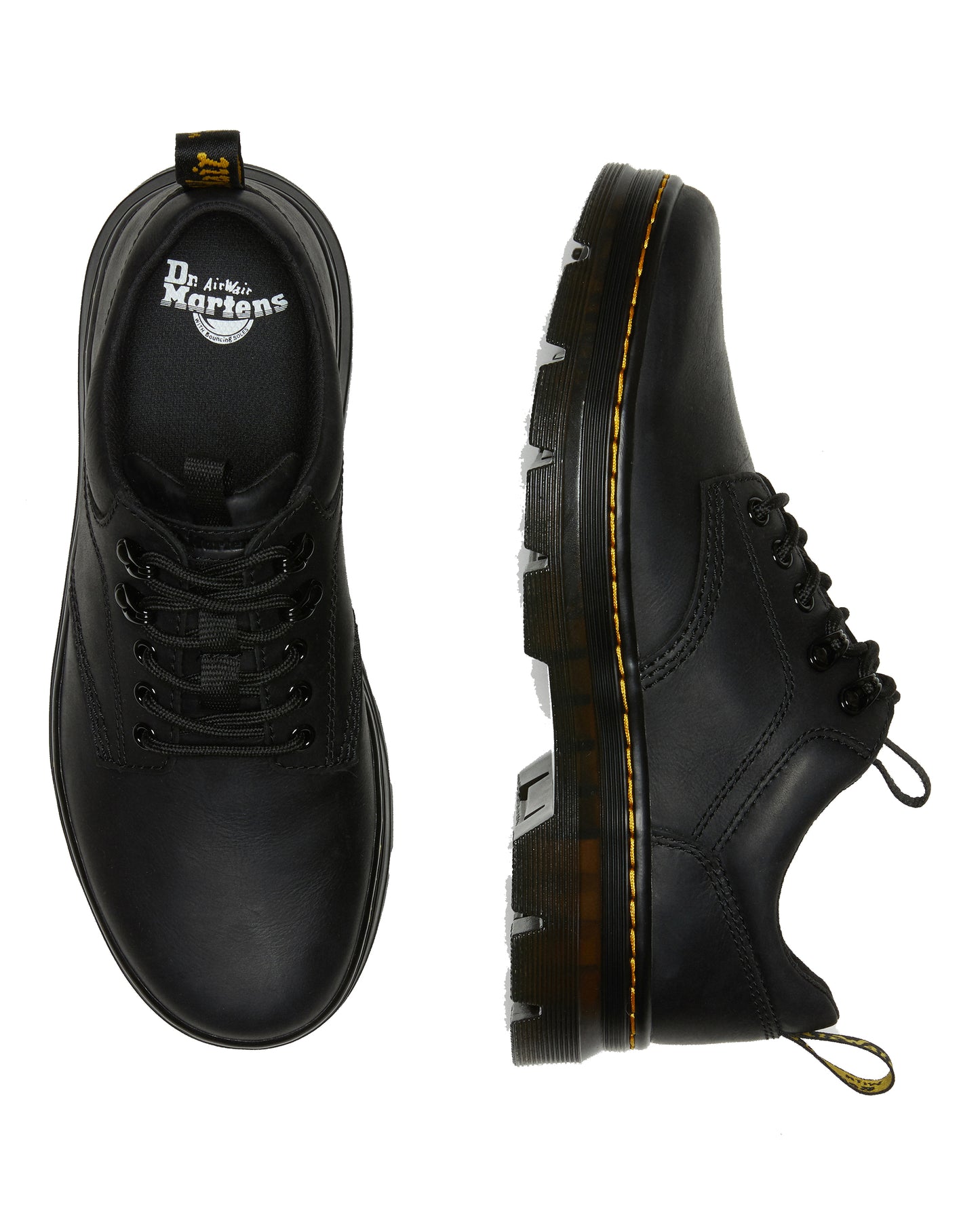 Two matte black lace-up shoes. One shows the toe with a rounded shape and black laces. The other shows the side profile with thick ridged sole and yellow seam.