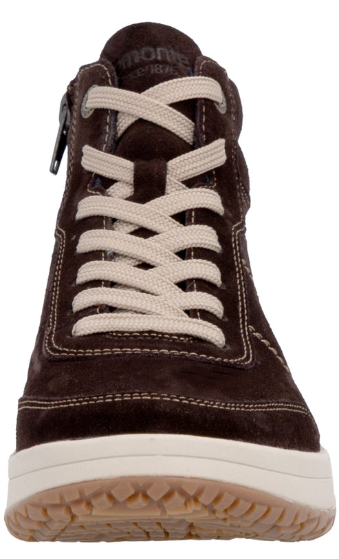 A front-facing close-up view of a dark brown suede high-top sneaker with cream-colored flat laces, visible light-colored contrast stitching, a thick off-white rubber midsole, and a tan textured rubber outsole.