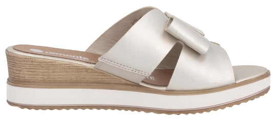 A light gold slip-on sandal with thick criss-cross straps and a low wedge heel.