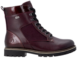 A maroon ankle boot with a lace-up front, a thick black lug sole, and a combination of smooth and patent leather-like panels with black laces and metallic hardware.
