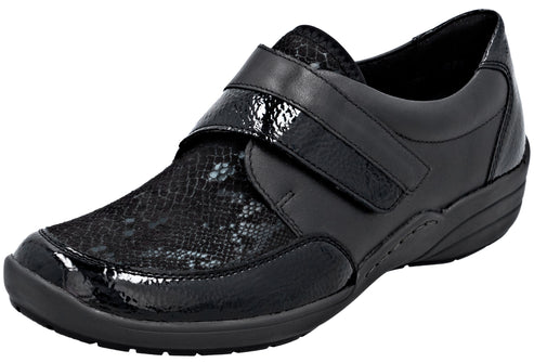 A black orthopedic-style women's shoe with a textured, snake-skin pattern on the toe and a glossy patent leather toe cap and velcro strap closure.