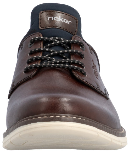 A brown leather casual shoe with white sole, dark blue tongue, and patterned laces viewed from a front-facing perspective.