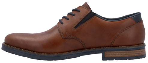 A brown leather oxford shoe with dark blue laces, a dark blue elastic side panel, and a dark blue lug sole with a layered wood-tone heel.