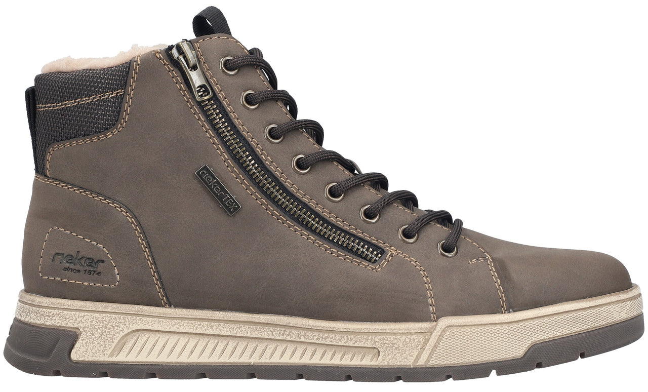 A brown leather ankle boot with a beige textured midsole, a dark brown lugged outsole, a side zipper, and dark brown lace-up closure featuring a fur-lined interior and the text "rieker" embossed on the side.