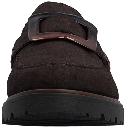 Close-up, front-facing view of a dark brown suede loafer with a thick, rugged black lug sole and a large, dark rectangular plastic buckle detail across the instep.