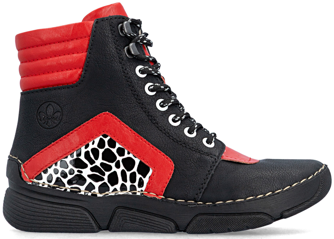 A black and red lace-up ankle boot with a high-top design, featuring a black faux leather base, red padded collar and chevron accent, and a black and white giraffe-patterned panel on the side, set on a thick black rubber sole with visible white stitching.
