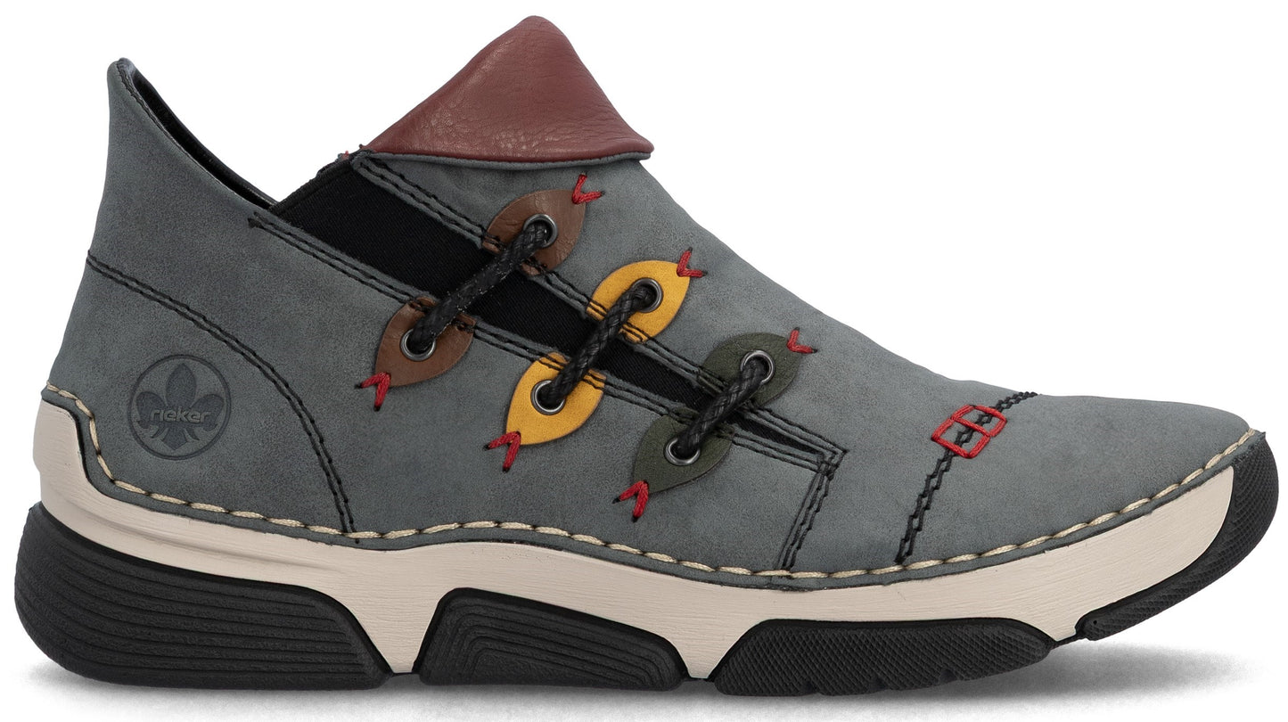 A gray casual shoe with a distinctive asymmetrical lacing system featuring yellow and brown eyelet tabs, a brown collar accent, a light-colored midsole, a thick black ridged outsole, and a debossed logo on the heel.