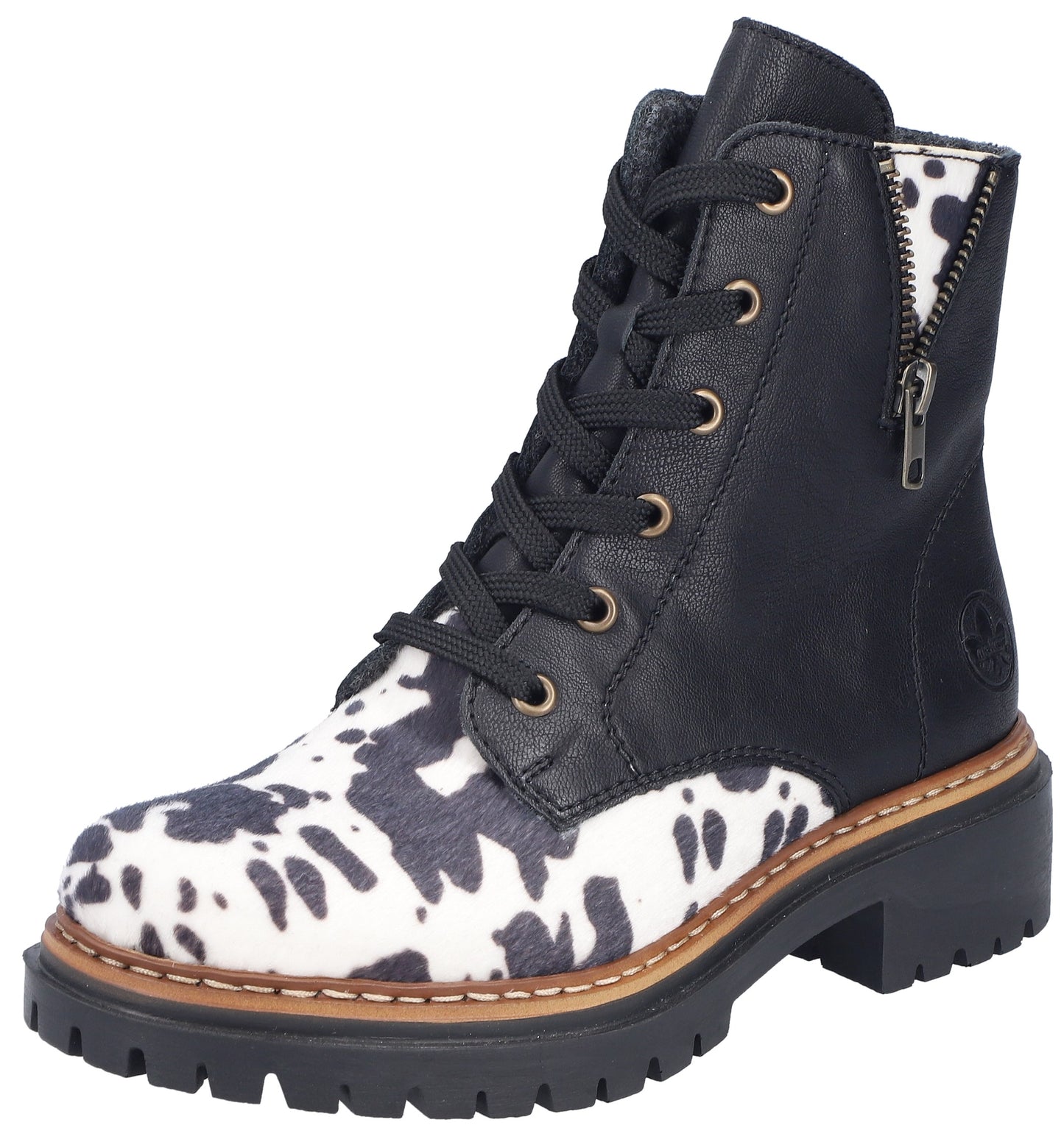 A black leather lace-up ankle boot featuring a white and black cow-print pattern on the toe box and side panels, a thick black lug sole with tan stitching detail, and a side zipper closure.