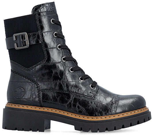 A black ankle boot with a textured, crocodile-skin pattern, featuring a side buckle strap, lace-up front with silver eyelets, and a thick, lugged rubber sole with a tan welt stitch.