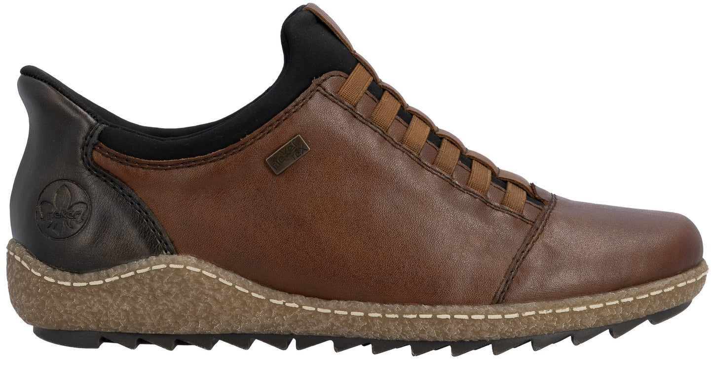 A brown leather slip-on shoe with a black collar and heel patch, featuring a tan, speckled textured midsole with white stitching and a black serrated rubber outsole.
