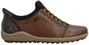 A brown leather slip-on shoe with a black collar and heel patch, featuring a tan, speckled textured midsole with white stitching and a black serrated rubber outsole.