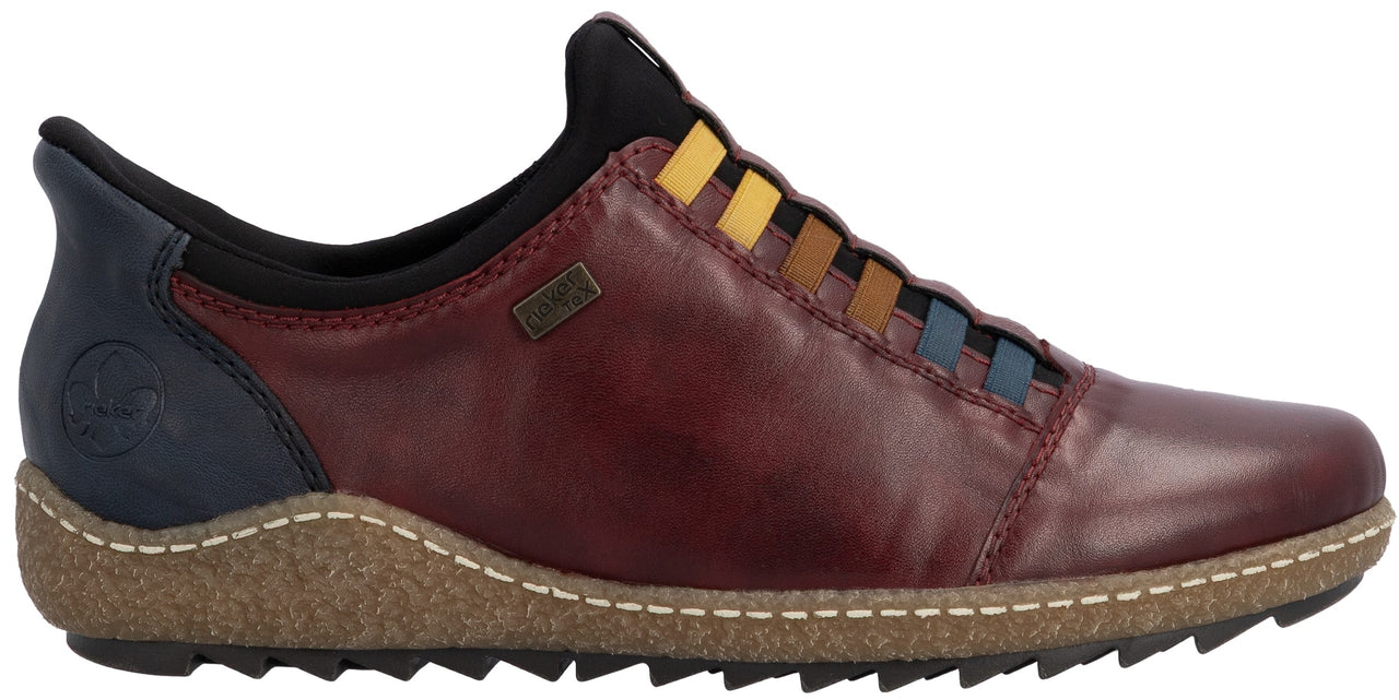 A slip-on shoe with a deep burgundy leather upper, a navy blue heel counter, and a textured tan midsole with contrast stitching. The vamp features a series of multi-colored, decorative horizontal bands in yellow, tan, and blue.