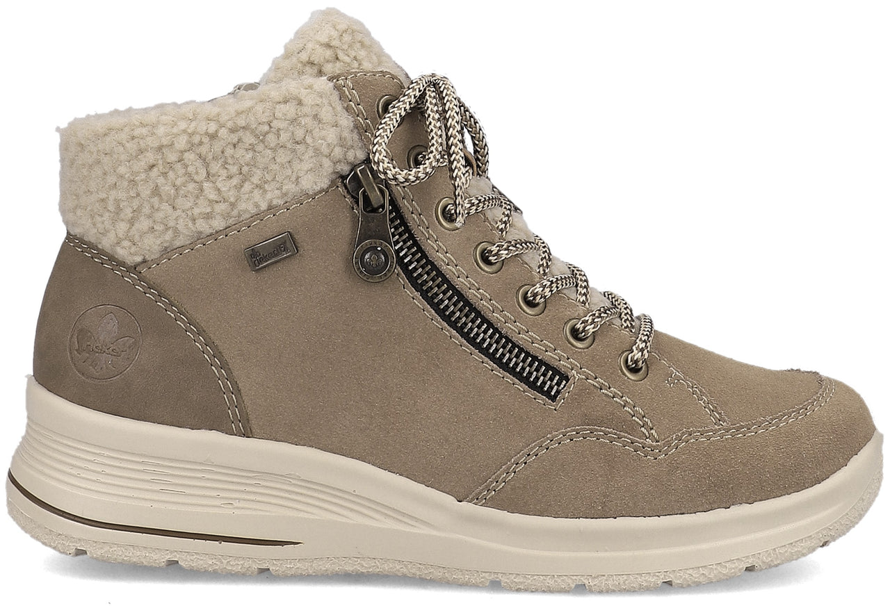 A tan suede ankle boot with a beige faux-shearling cuff, decorative side zipper, lace-up front, and a thick, textured beige rubber sole.