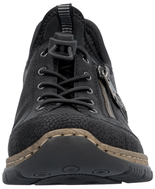 A close-up, head-on view of a black, textured, sneaker-style shoe with a drawstring lace closure, a side zipper, and a tan, stitched welt above a dark sole.