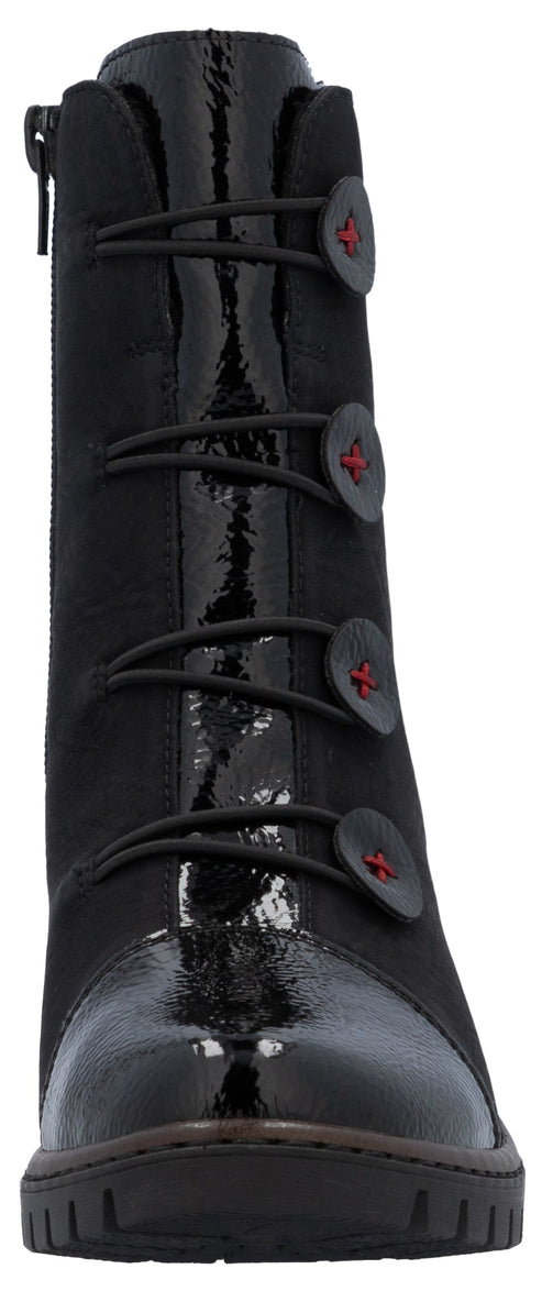 A black ankle boot with a glossy patent leather toe cap and front panel. The upper is made of a matte fabric, and the front features a decorative closure with four black, circular buttons secured by elastic loops, each accented with a small red embroidered cross in the center. The boot has a thick, dark rubber sole with a treaded pattern.