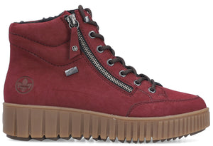 Red ankle boot with zipper, decorative laces, and thick ribbed brown sole.