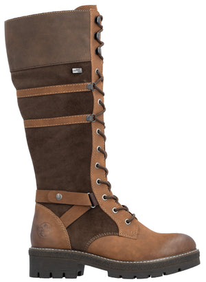 A tall, knee-high lace-up boot crafted from a mix of brown suede and smooth tan leather, featuring a rugged, dark-brown lugged rubber sole, decorative side straps with metallic hardware, and a classic lace-up front with metal eyelets.