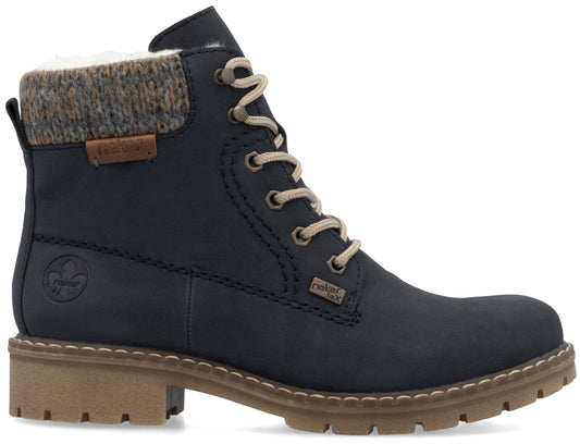 A dark navy blue ankle boot with a beige knit cuff at the collar, a beige lace-up front, a thick tan lug sole, and the Rieker brand logo embossed on the side.