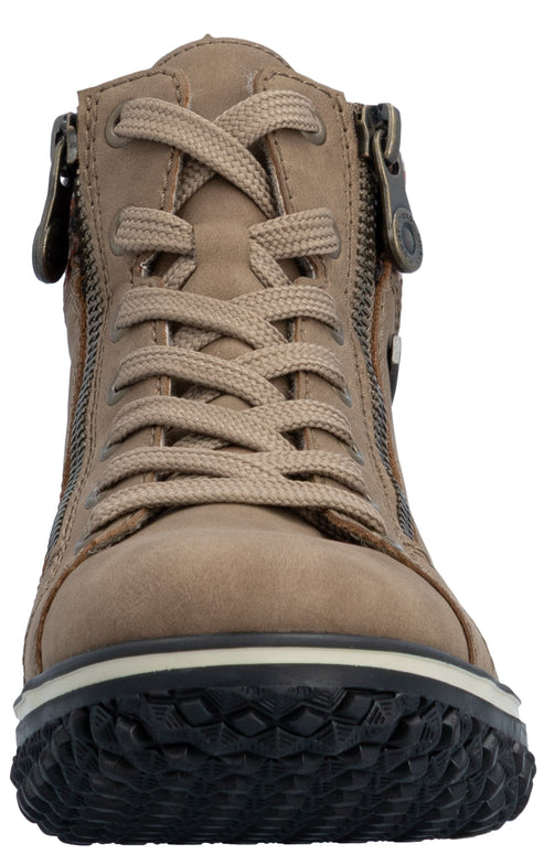 A close-up, front-facing view of a beige, lace-up ankle boot with zippers on both sides of the tongue and a thick, textured black rubber lug sole.
