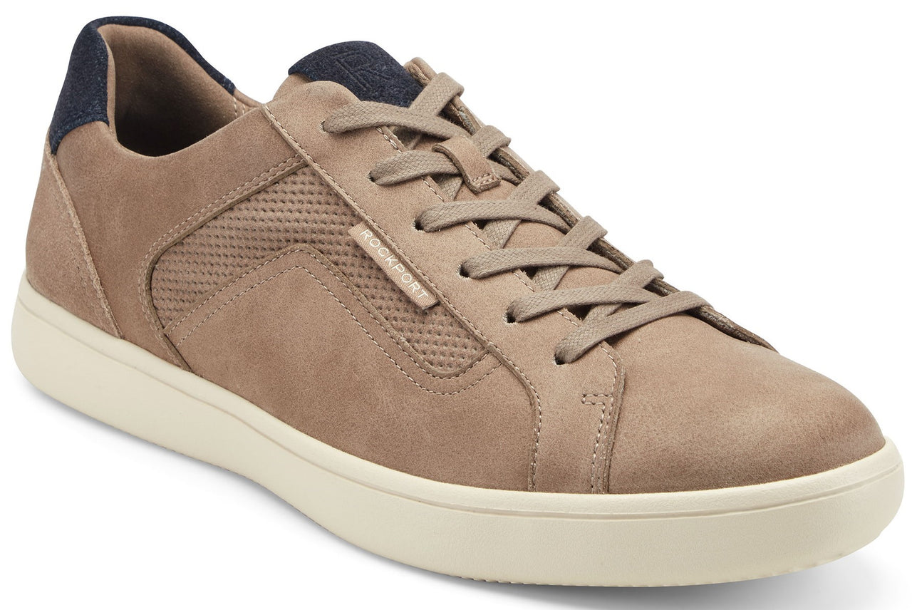 Tan-colored sneaker with a navy blue padded collar, tonal laces, perforated side panels and a cream colored sole.
