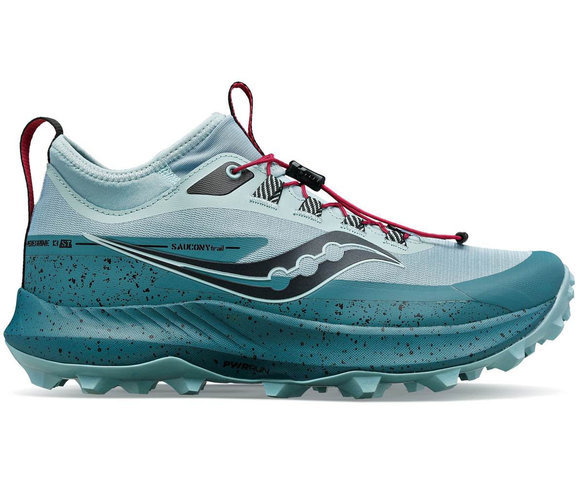 Trail running shoe, light blue upper with dark teal midsole and lugged outsole, red bungee laces, pull tab, and black logo.