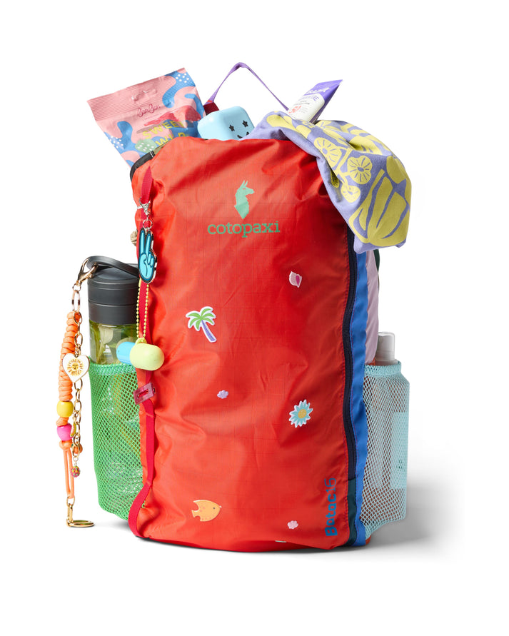 Open red backpack with filled side pouches and items stuffed into the top.