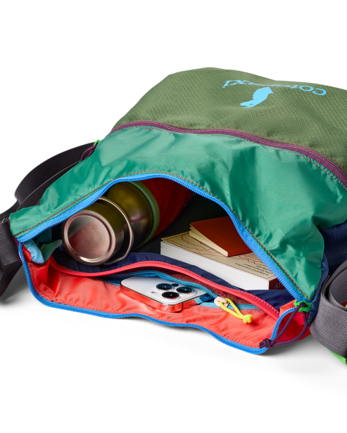 Open green bag with colorful interior showing a water bottle, notebook and phone.