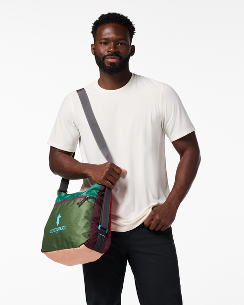 Person carrying a colorful shoulder bag with a logo on it.