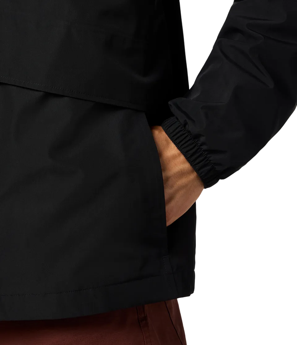 A person's hand inside a black rain jacket's pocket; the jacket sleeve has an elastic cuff.