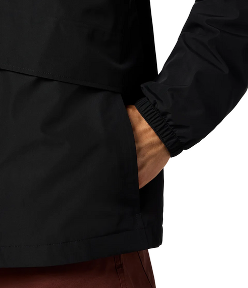 A person's hand inside a black rain jacket's pocket; the jacket sleeve has an elastic cuff.