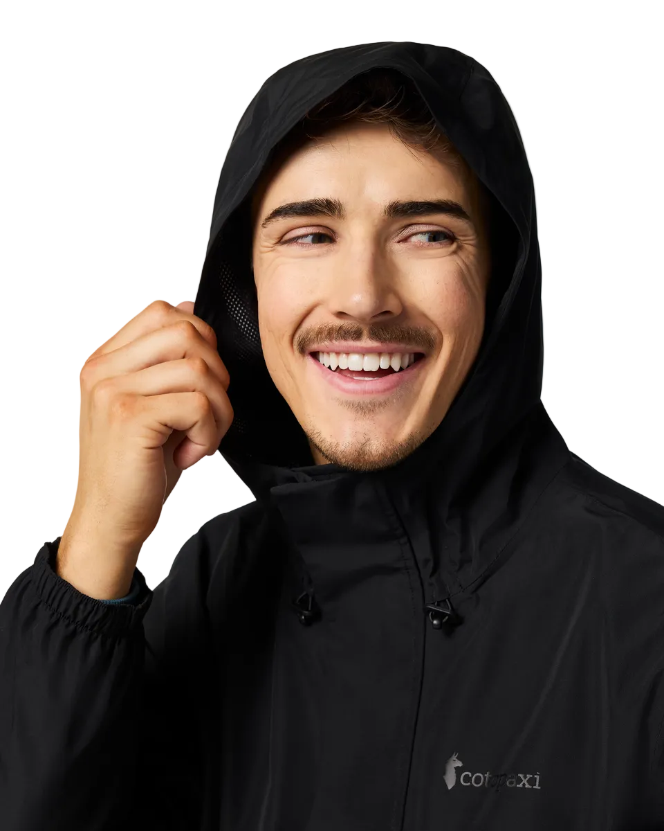 Man wearing a black hooded jacket with the hood up and a logo on the chest.