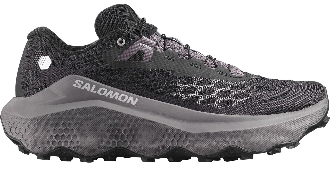 Trail running shoe with a black mesh upper, a grey honeycomb pattern on the midsole and toebox, visible SALOMON text on the side, and black laces.