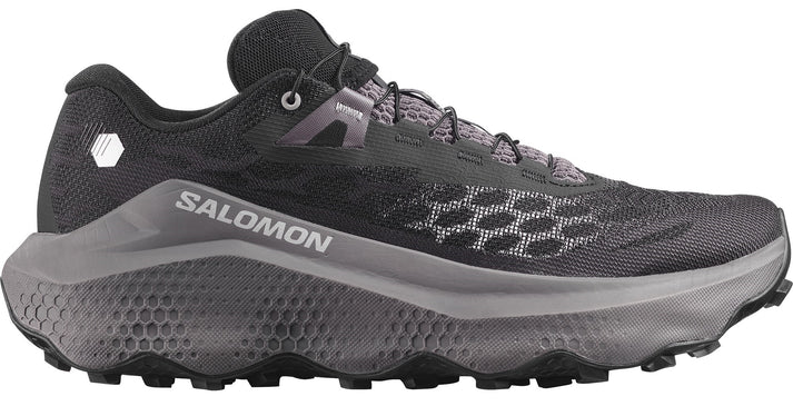 Trail running shoe with a black mesh upper, a grey honeycomb pattern on the midsole and toebox, visible SALOMON text on the side, and black laces.