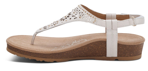 White sandal with decorative cutouts and an ankle strap.