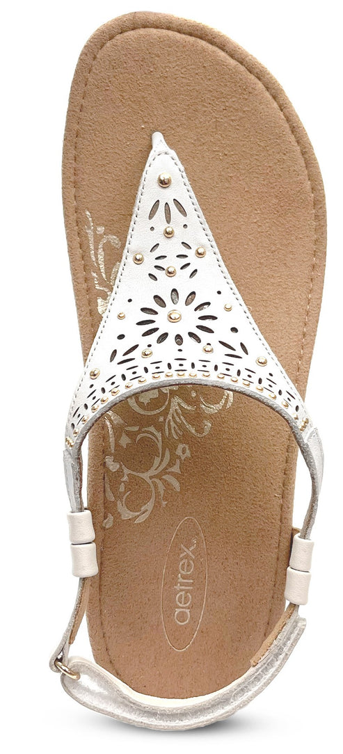 A beige sandal with a white, decorative strap.