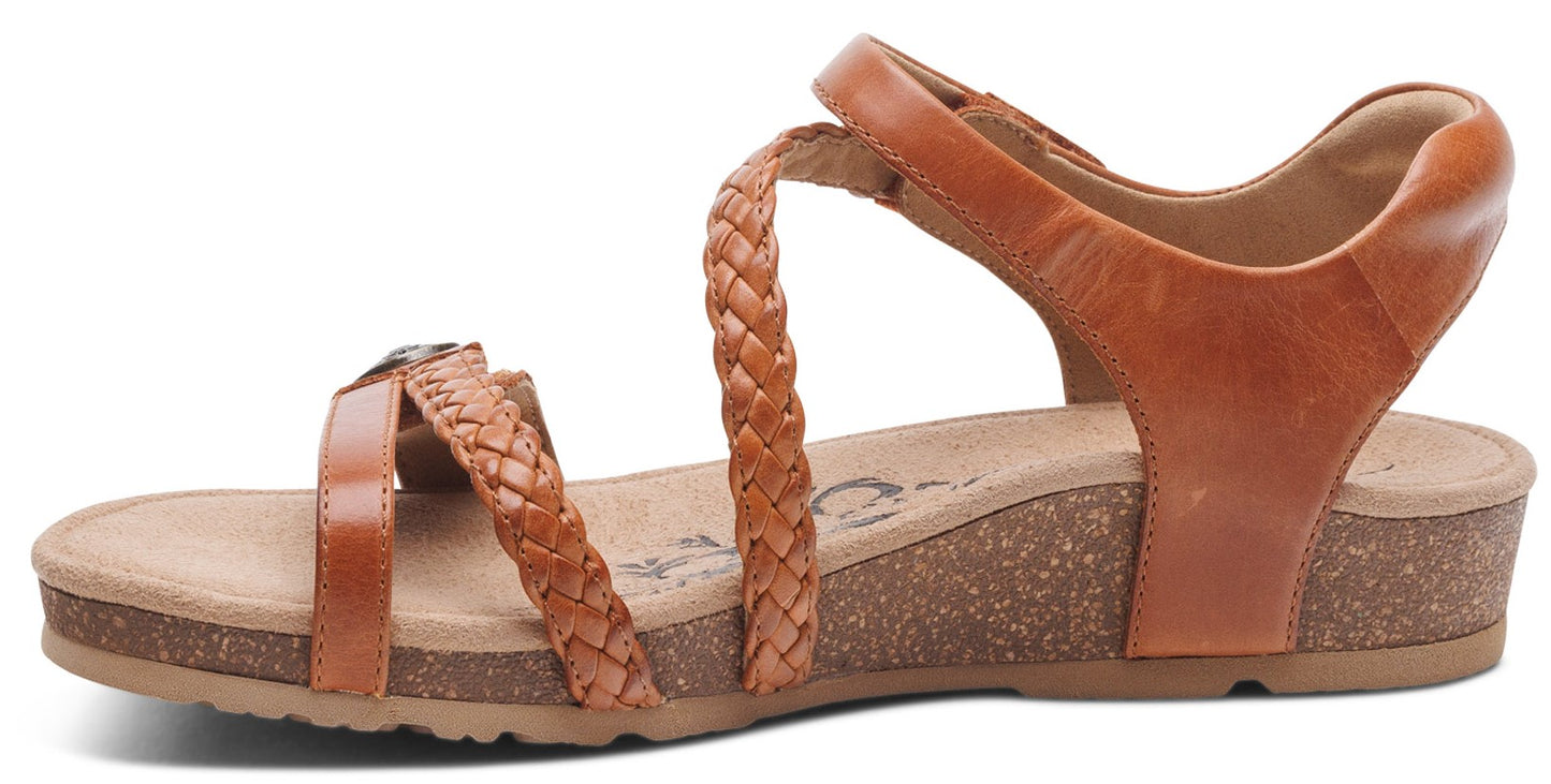 A brown sandal with braided straps, ankle strap, and a cork wedge heel.