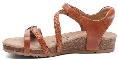 A brown sandal with braided straps, ankle strap, and a cork wedge heel.