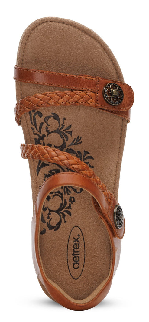 A brown sandal with braided straps and round metal details.