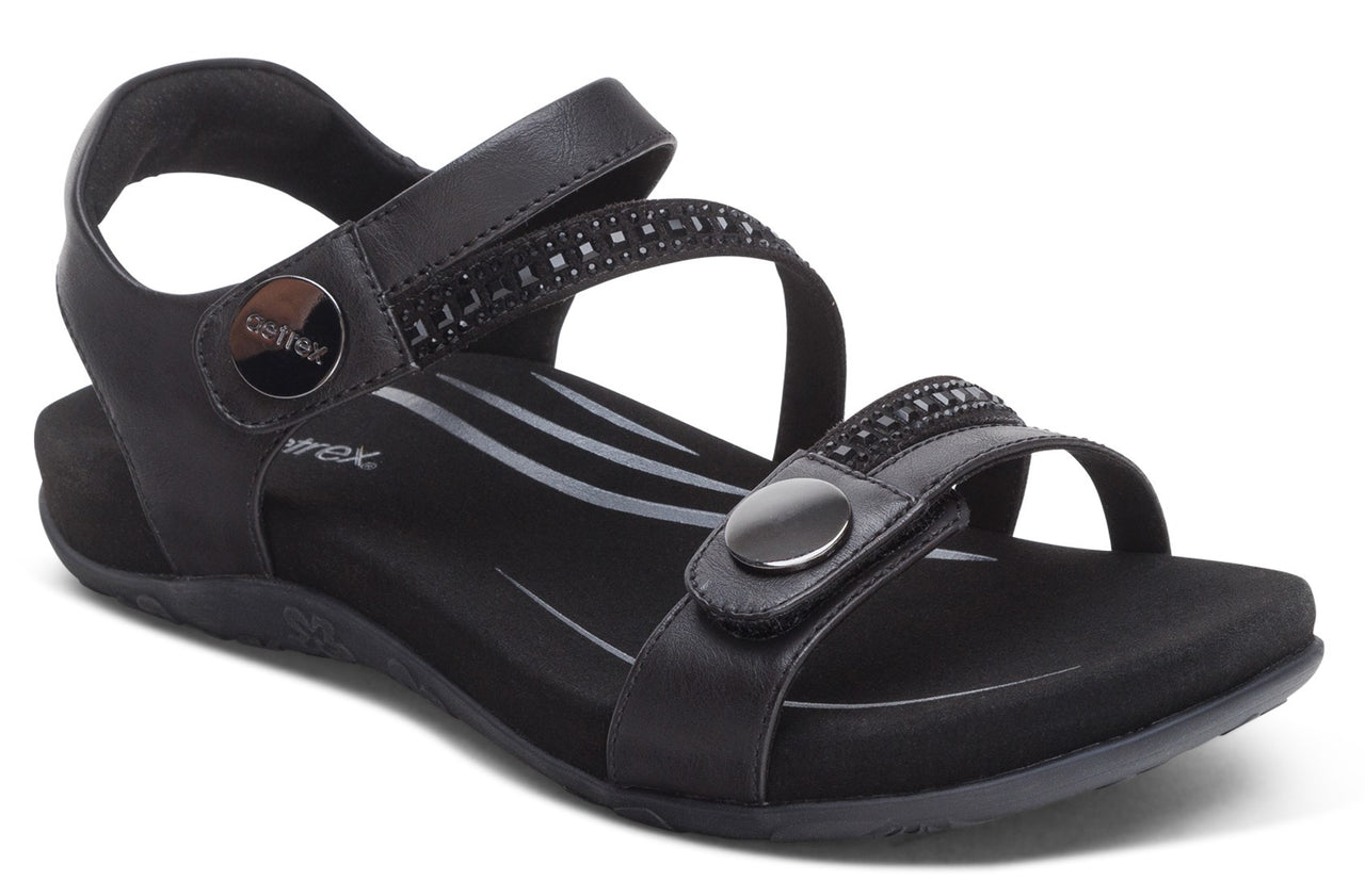 Black sandal with adjustable straps and decorative embellishments.