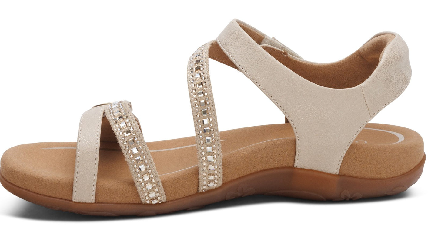 Beige sandal with criss-cross straps and rhinestone accents.